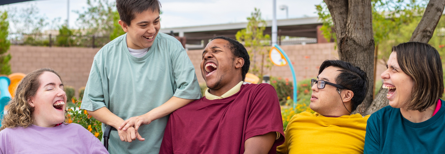 Group of five people sitting outside and laughing together