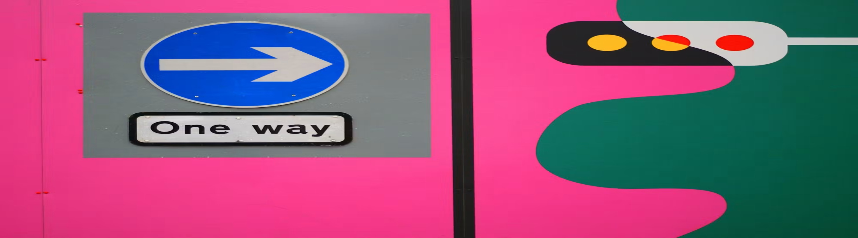 Photo of One-way sign on wall painted pink.