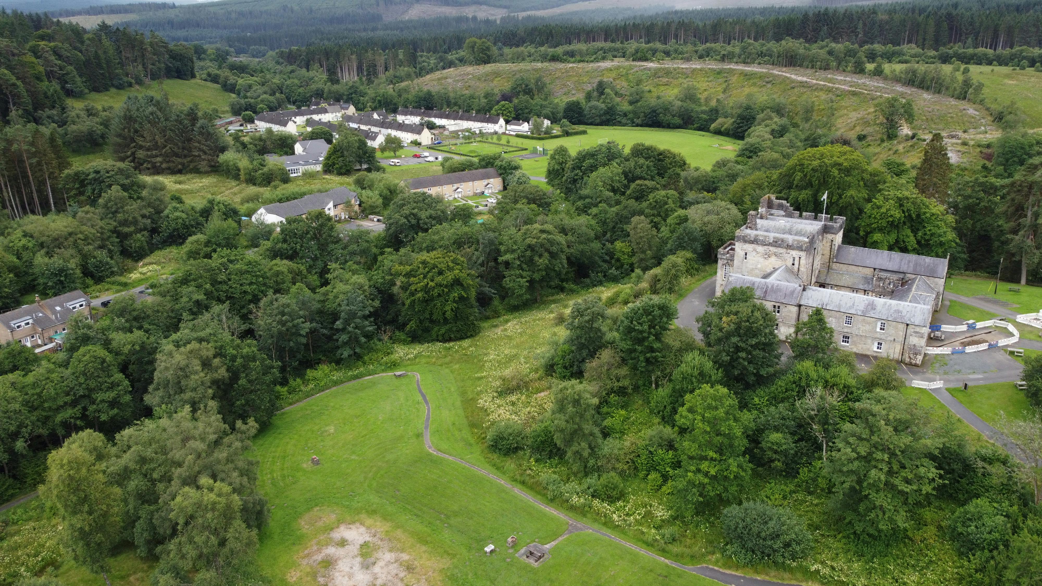 Drone photograph showing Kielder Castle, Butteryhaugh village, and the woodland concealing the Kielder Burn