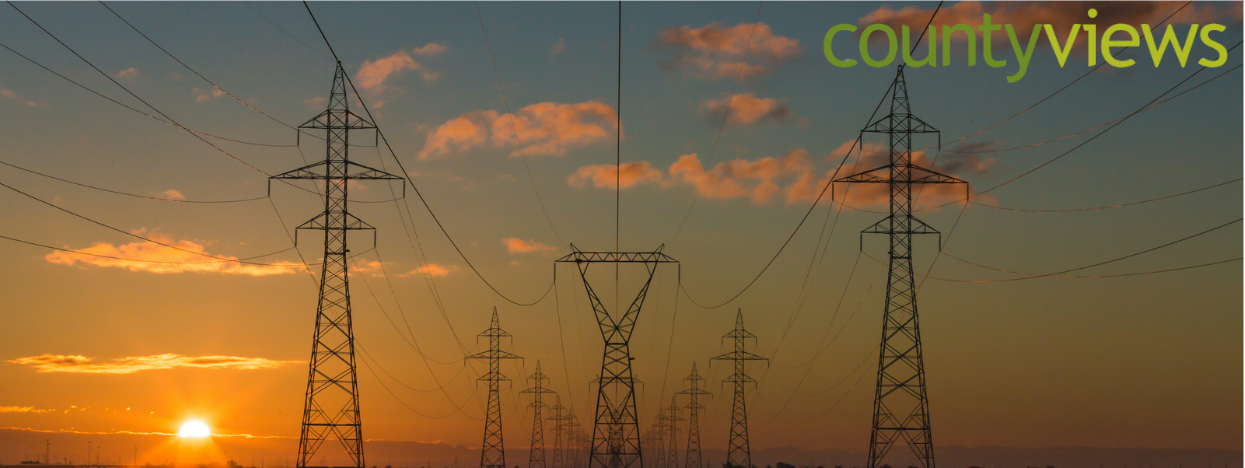 An image of a sunset with pylons and the county views graphic.