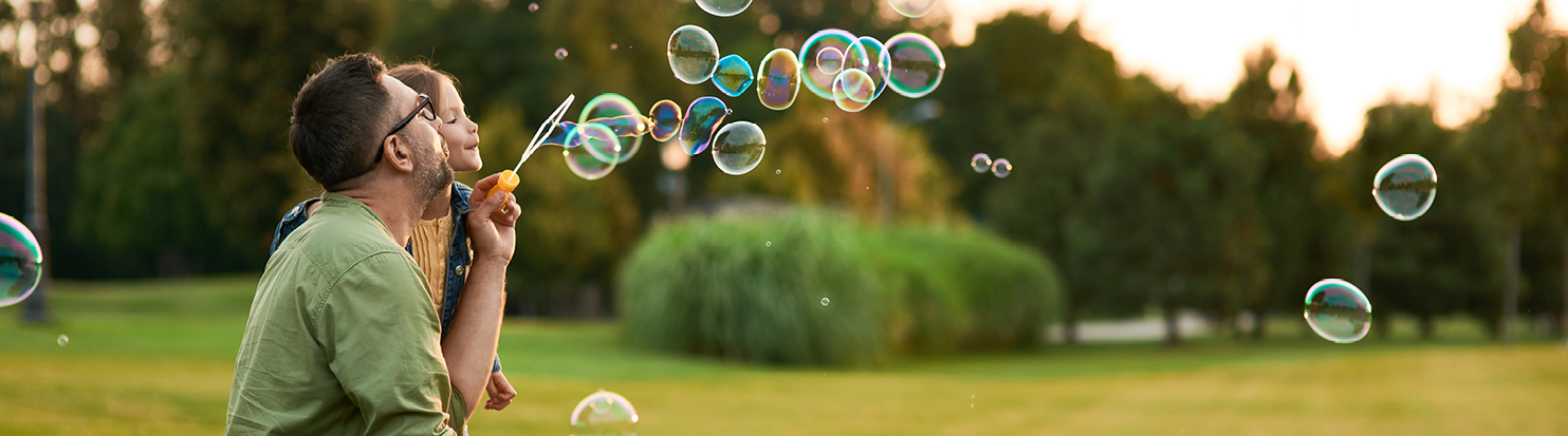 Man and child in a park blowing bubbles