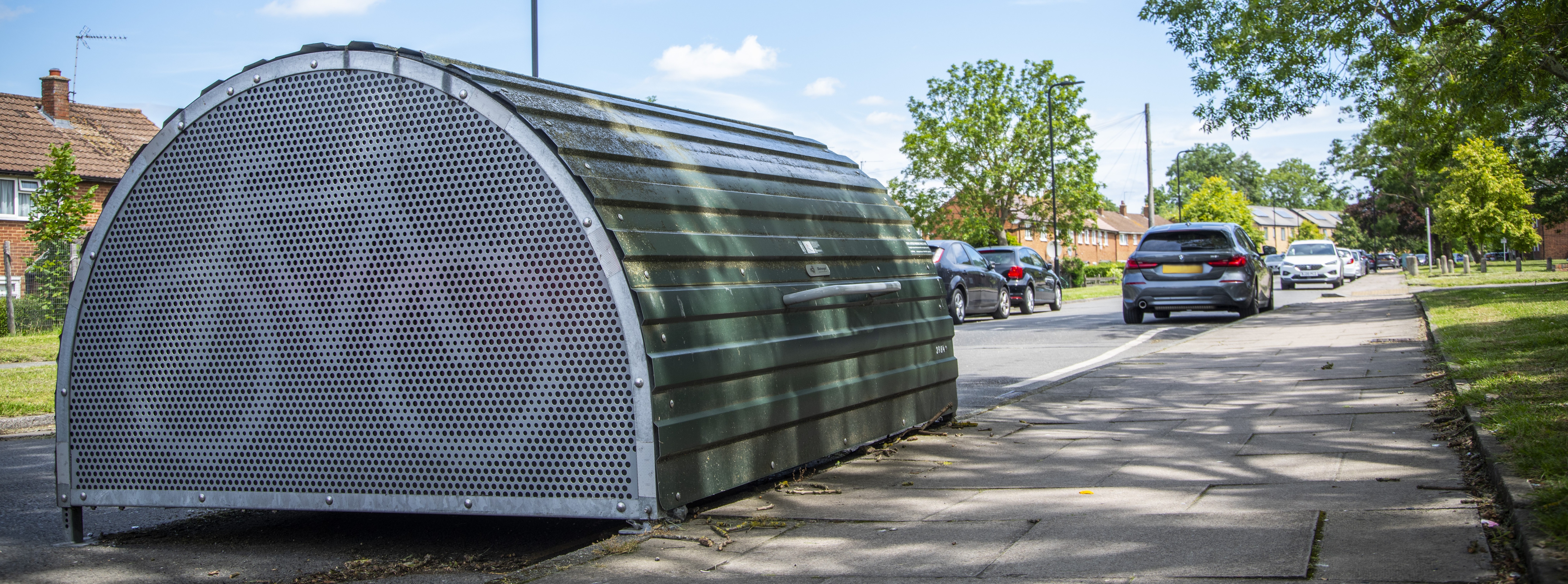 Image of a street in Harrow with a cycle hangar and parked cars 