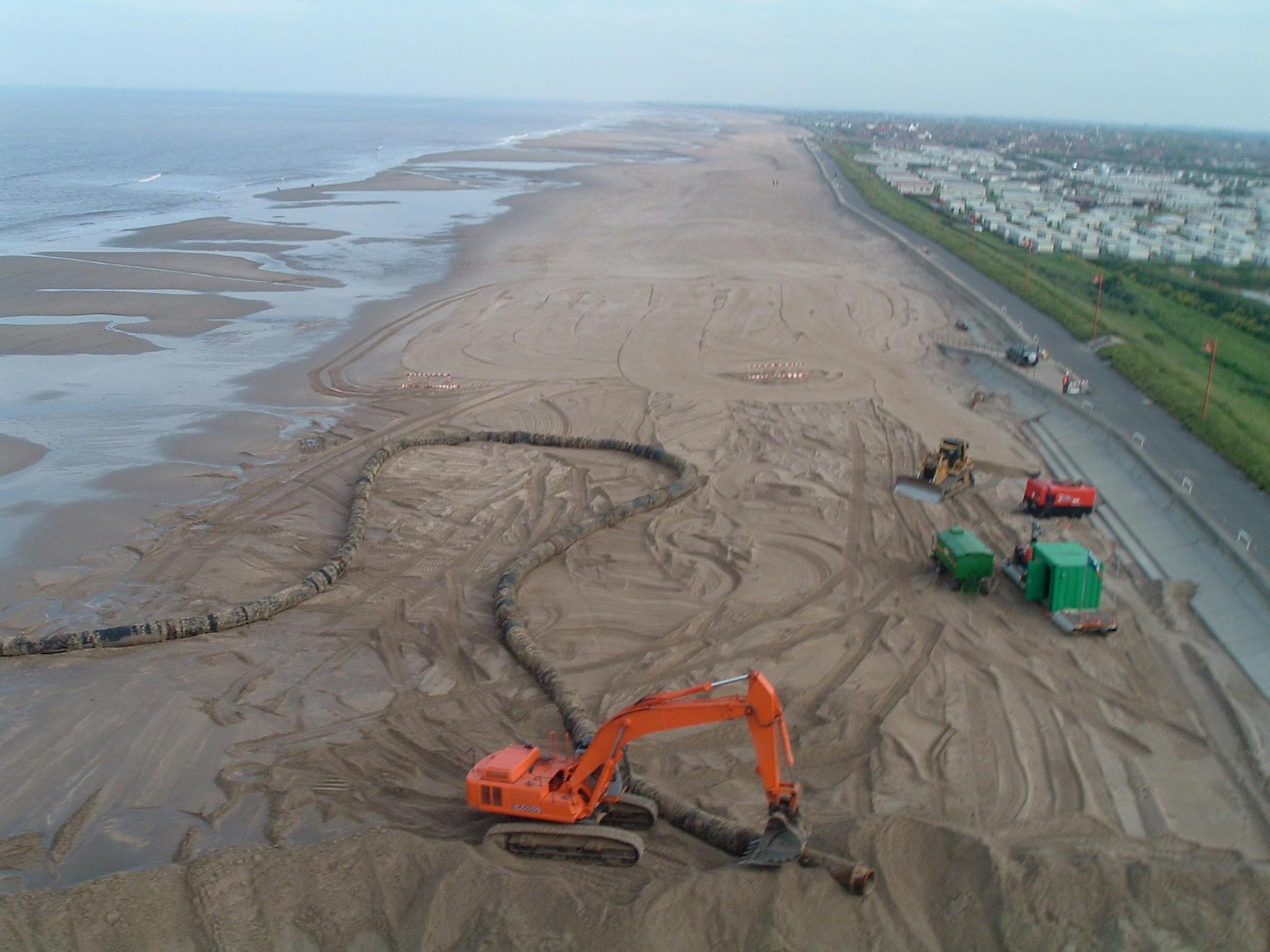 An aerial image of the sinkerline being moved by an excavator near a large caravan site