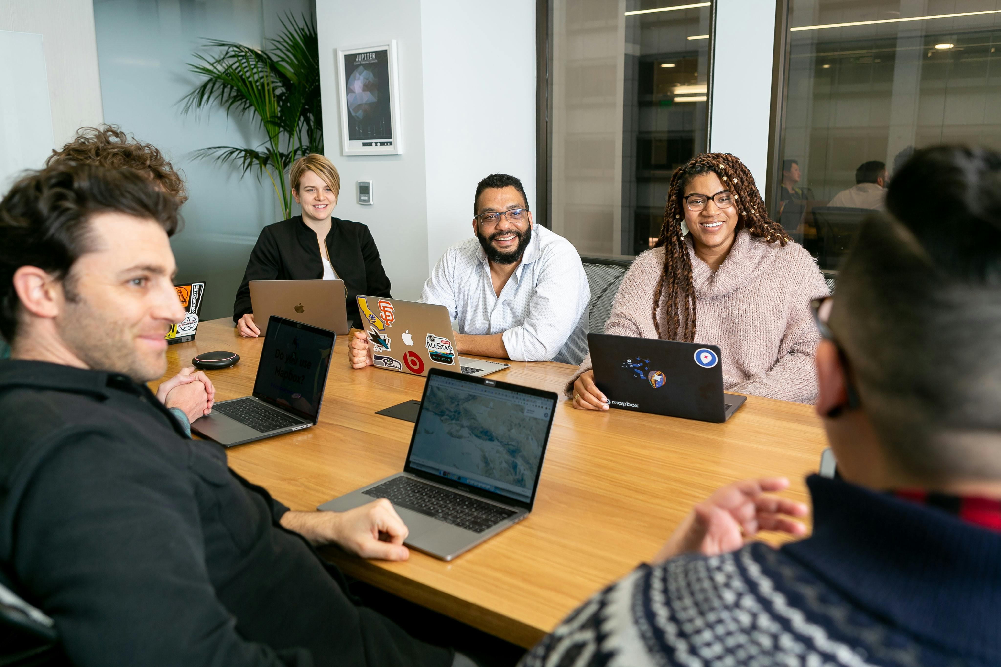 Group of casually dressed professionals sitting around a table in a relaxed meeting.