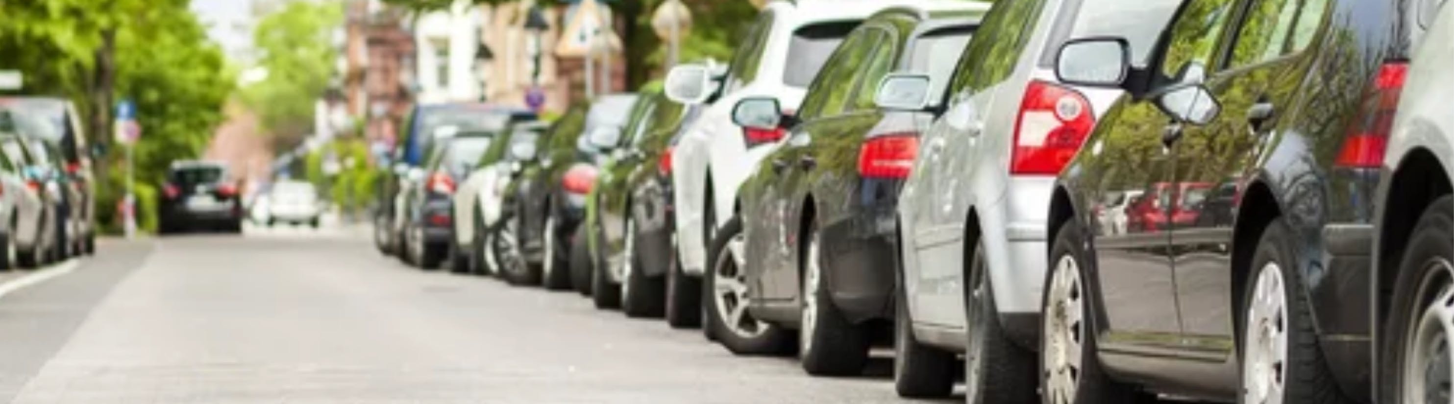 Photo of vehicles parked on right-hand side of road.