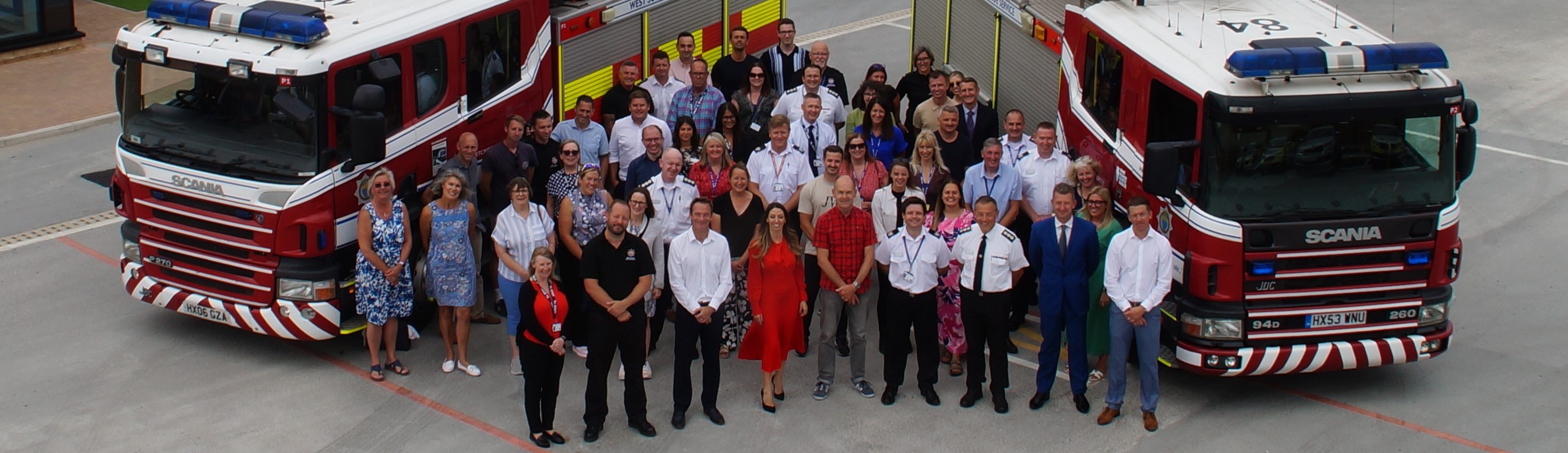 Members of staff from West Sussex Fire & Rescue Service standing between two fire trucks