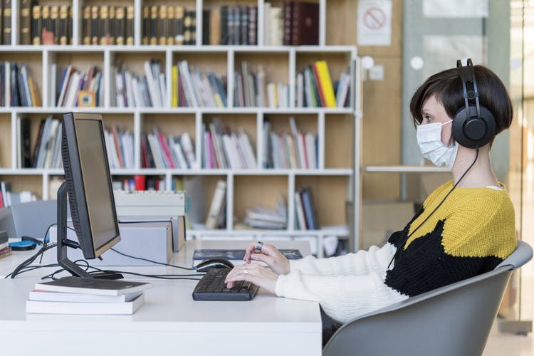 Photo of a person sitting at a computer in a library