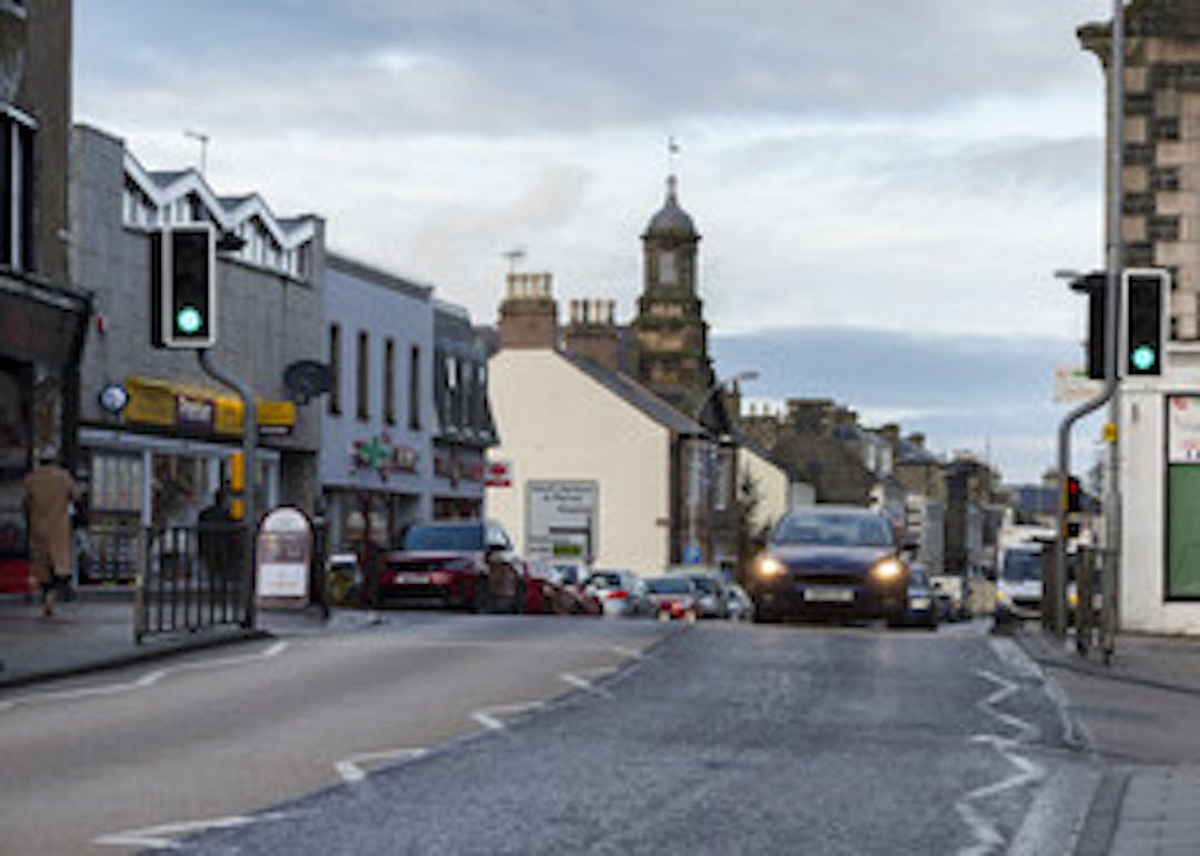 Photo of the High Street in Banff with shop fronts and the main road.