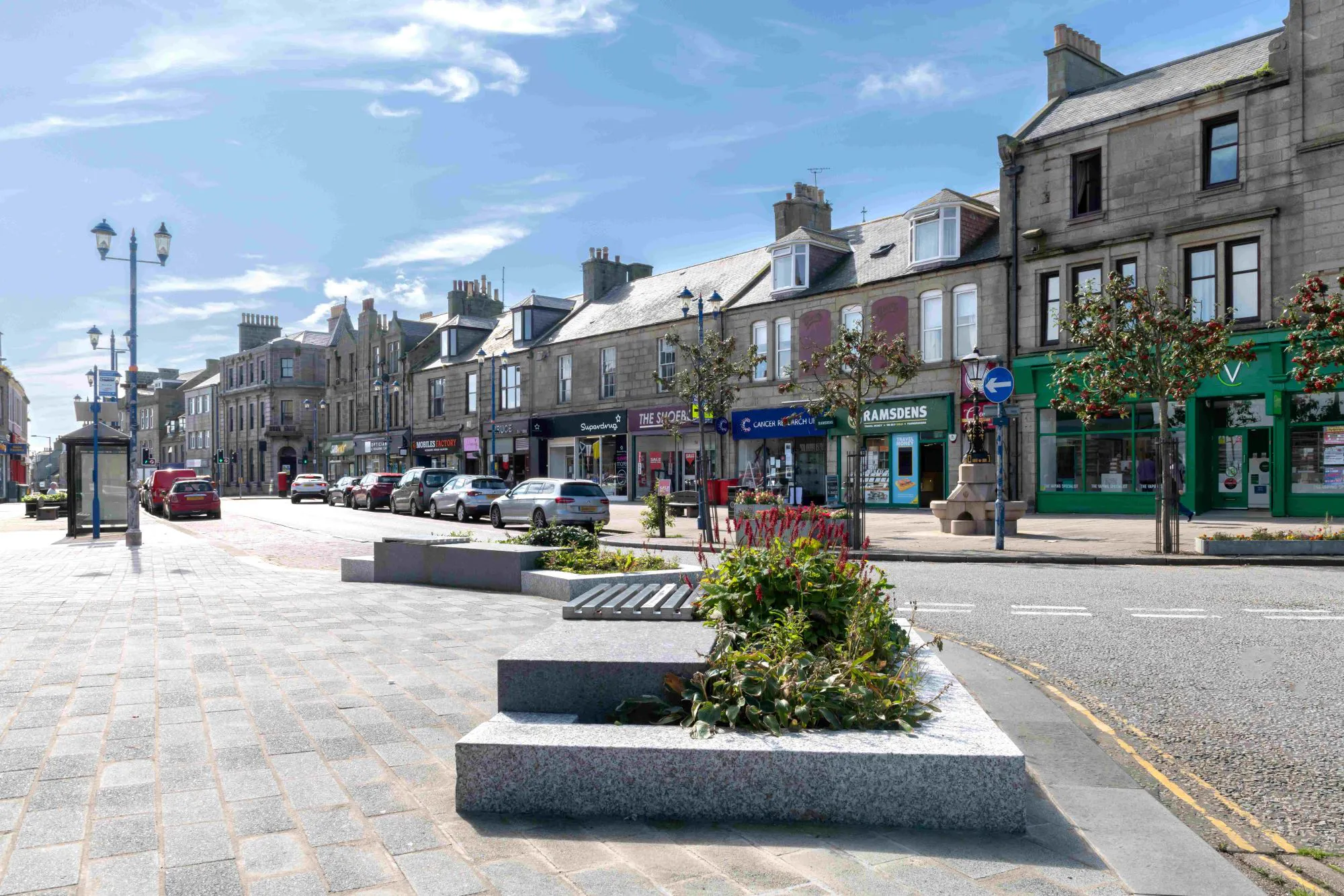 Image of Fraserburgh town centre with shops, trees, lampposts, people, road and pavement with the Fraserburgh BIG Ideas logo