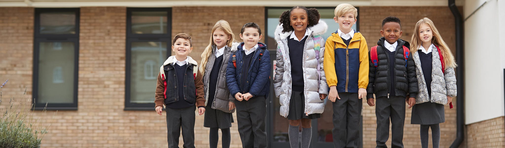 Primary school pupils standing in front of their school