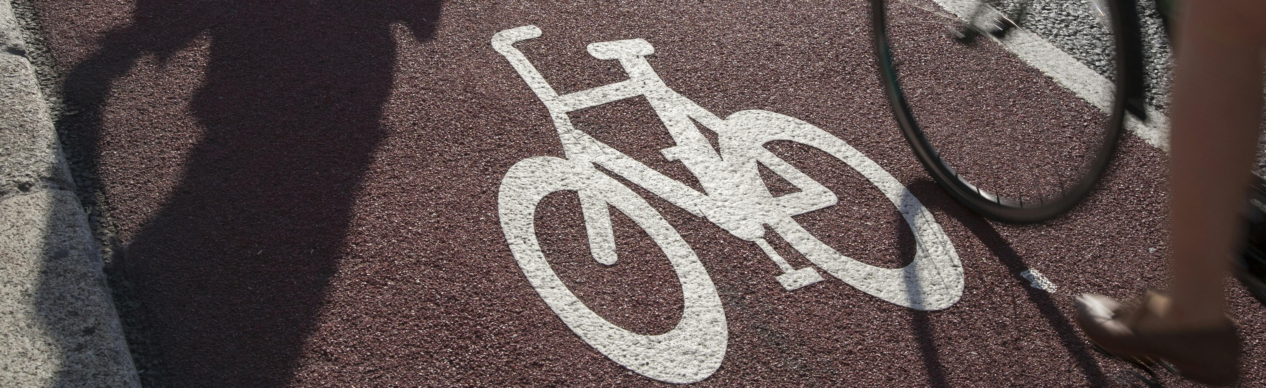 Photo of red cycle lane with painted pedal cycle symbol.