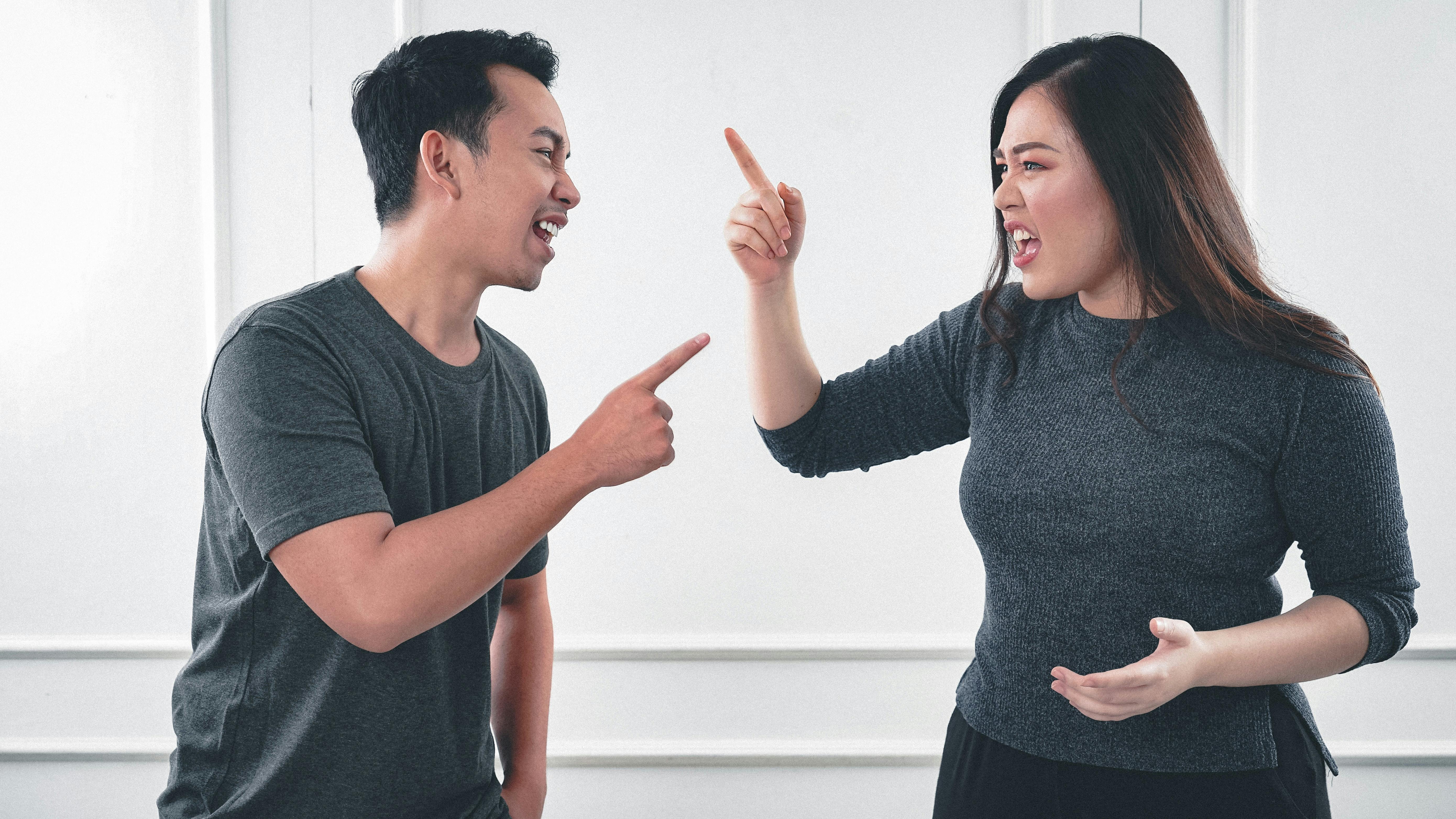 A man and a woman arguing and pointing fingers at each other