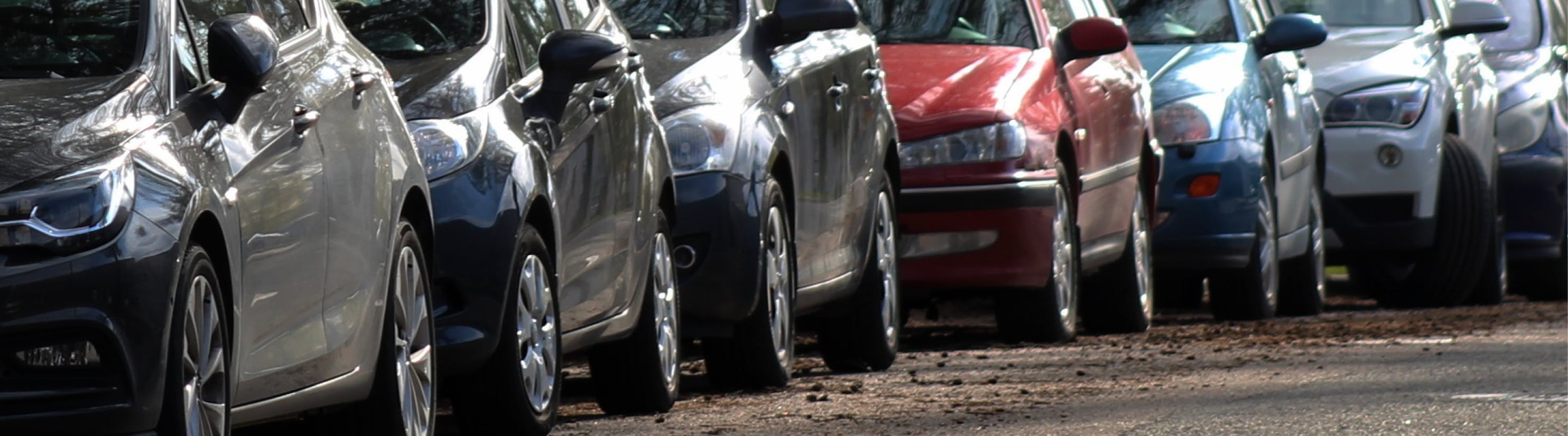 Photo of cars parked on left hand side of road.