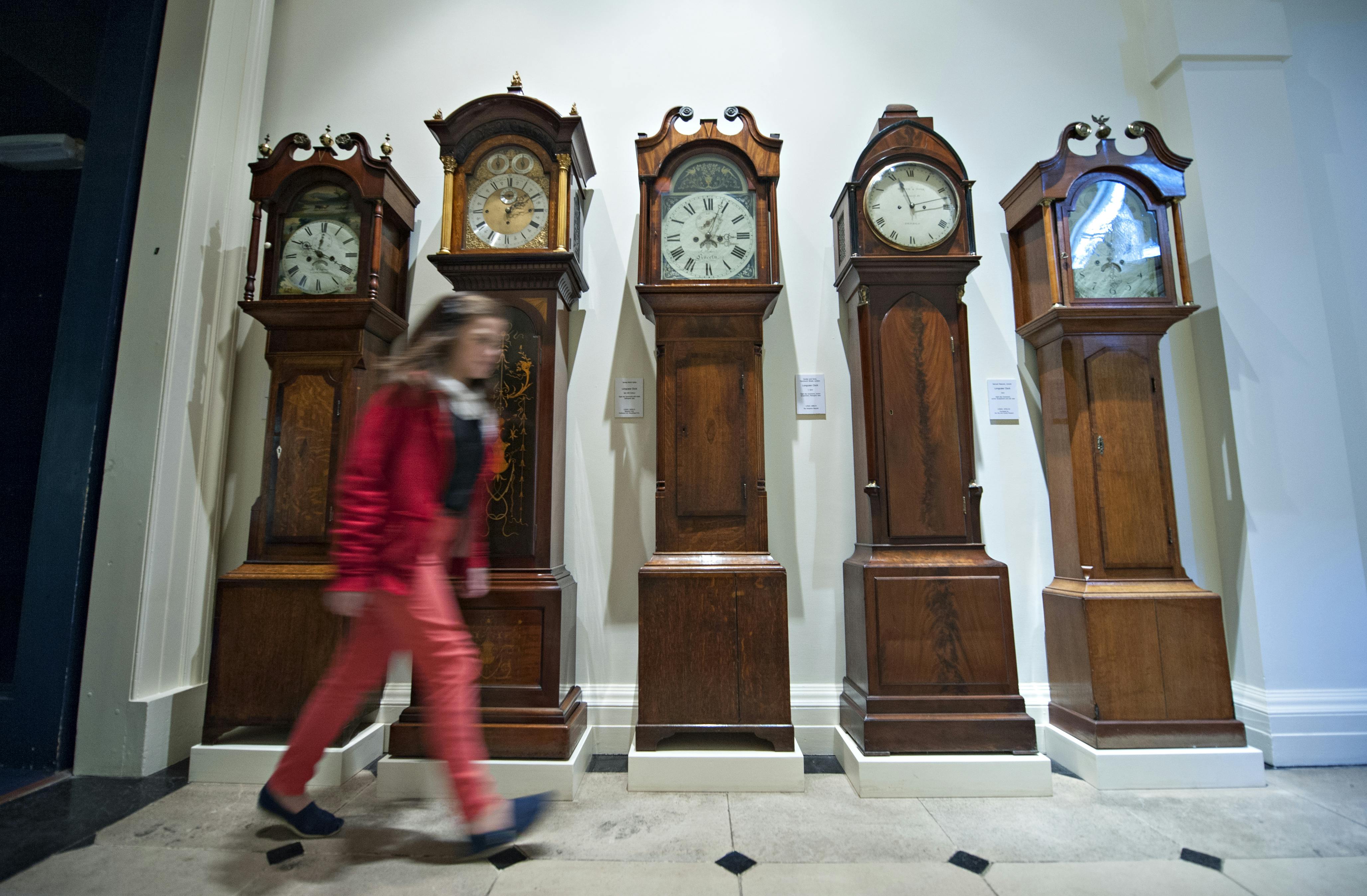 An image of the Longcase clocks with someone walking past them.