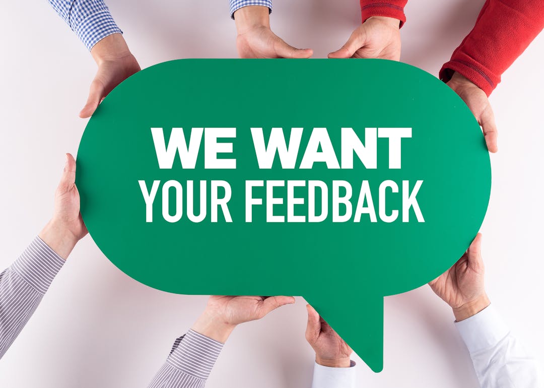 Hands holding a green sign saying we want your feedback