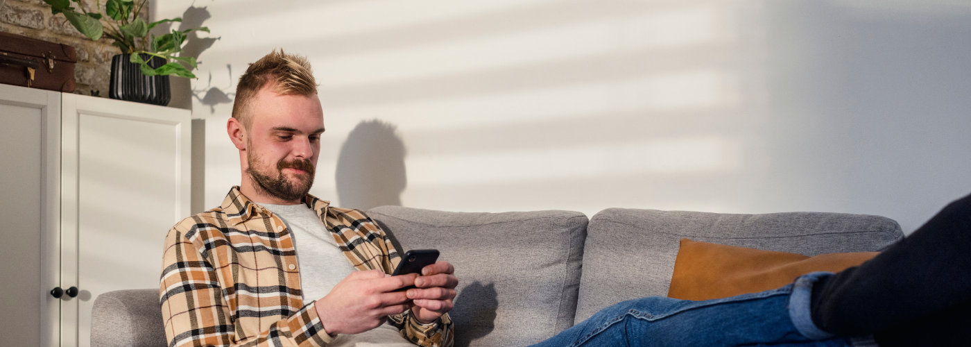 A man on his phone whilst on the sofa