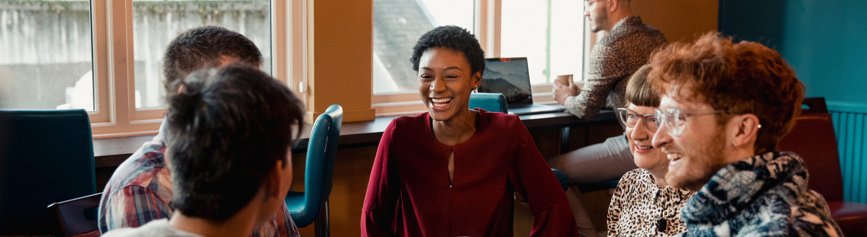 Image shows a group of people sitting around a table talking
