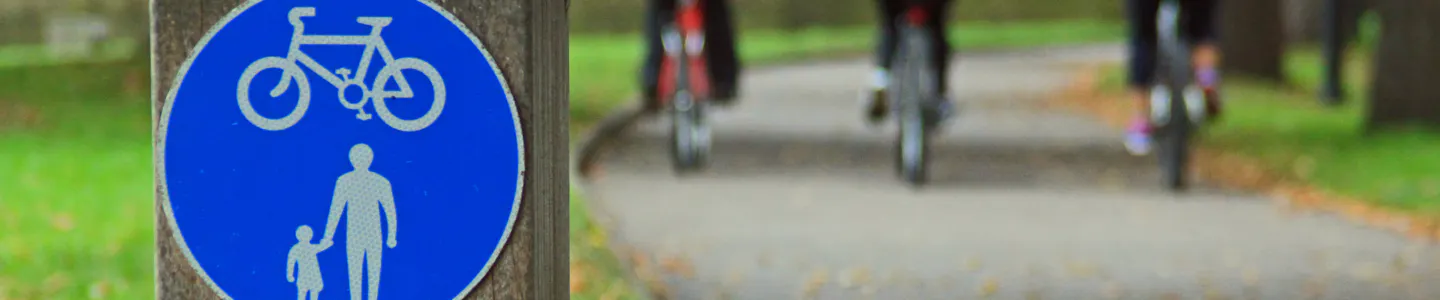 Cycle path sign with three cyclists in the background