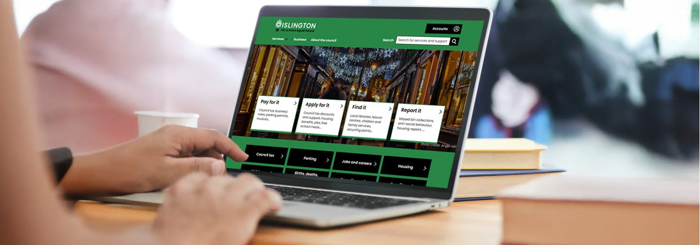 Hands on the keyboard of a laptop, typing. The Islington Council website is on the screen.