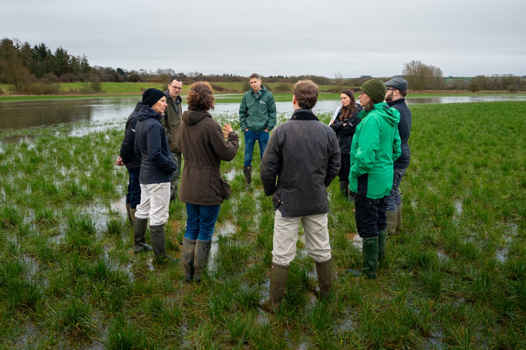 A photo of representatives from multiple agencies and the farm cluster in a field next to a river