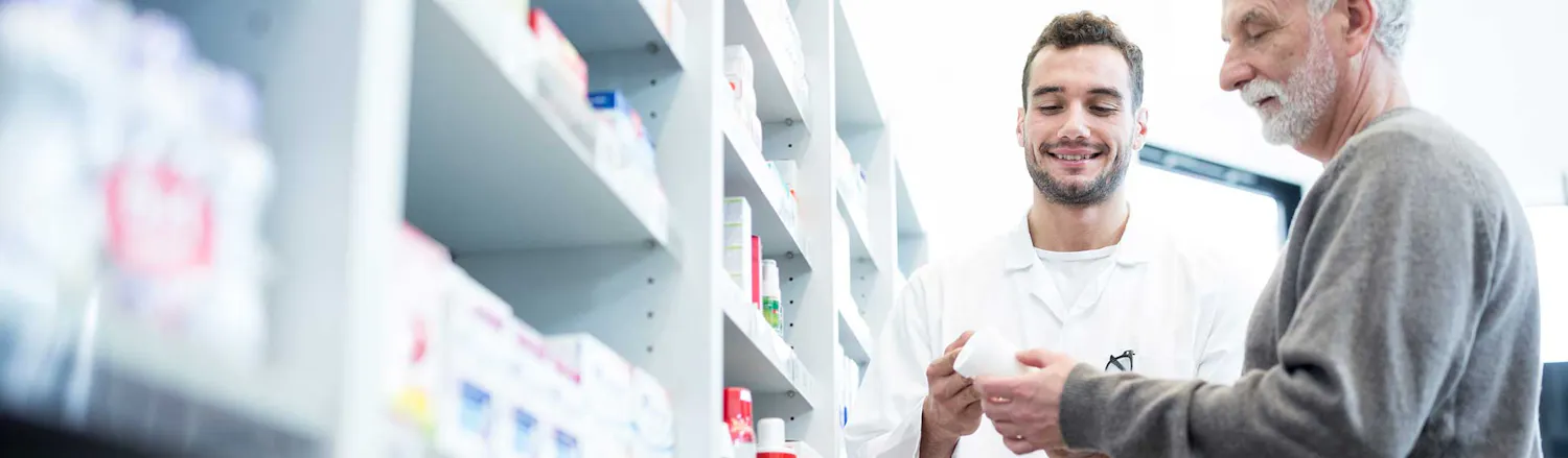 An image of two men looking at a bottle of tablets in a pharmacy