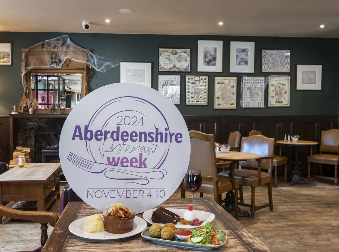 Aberdeenshire Restaurant Week sign placed on a table with plates of food at Farquharson's.