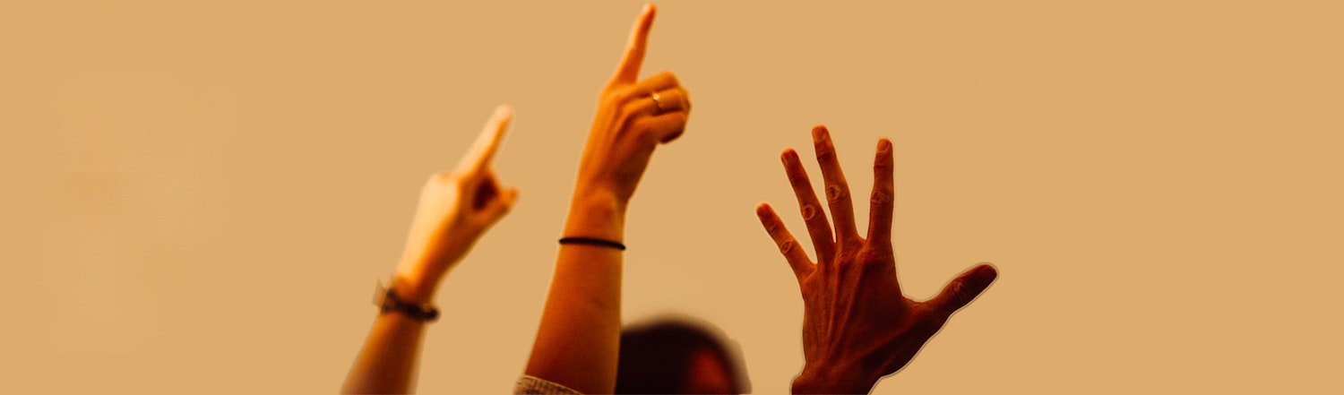 Three hands are in the air two of which have fingers pointing upwards