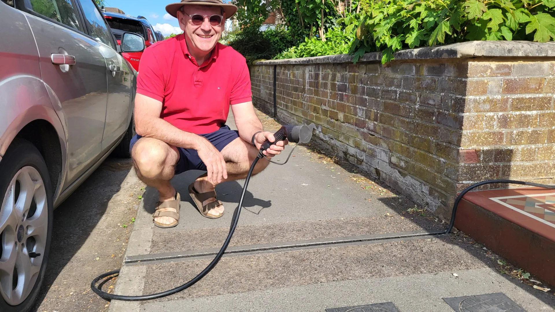 Photo of EV gully across a pavement with person holding a charger