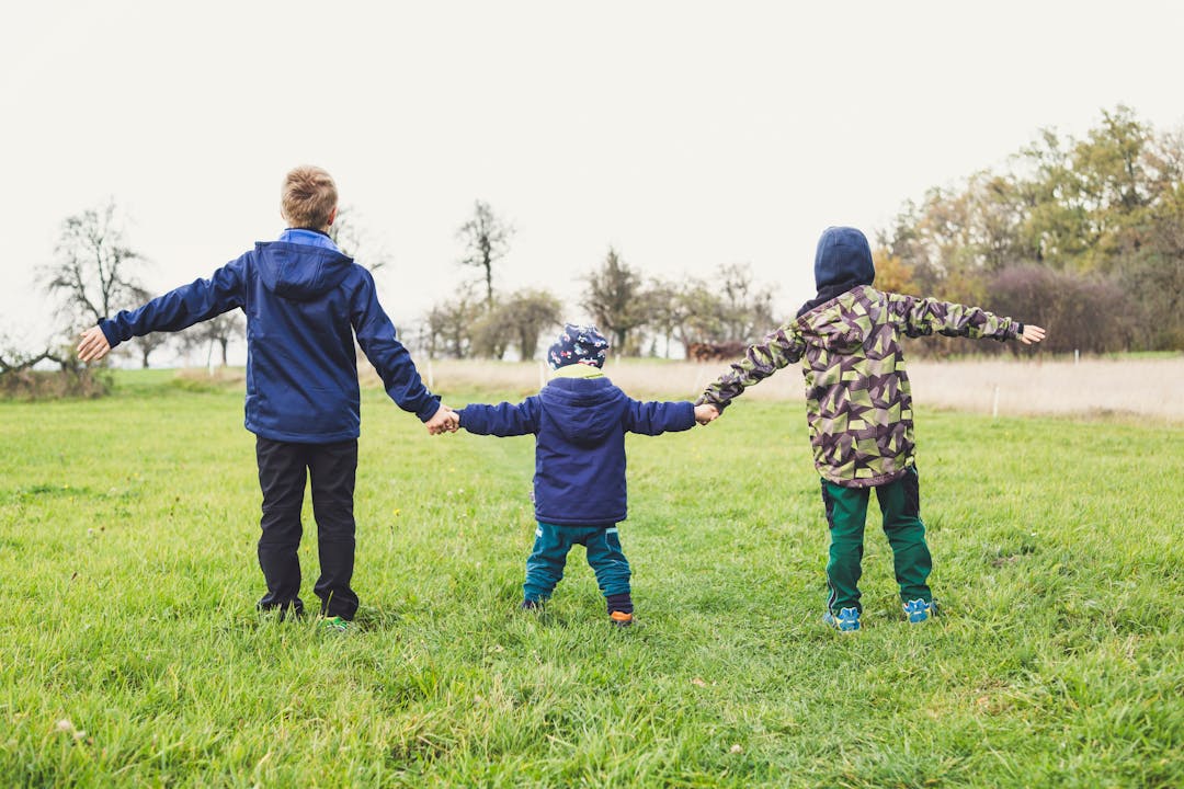 Parent and two children of different ages standing in a row holding hands