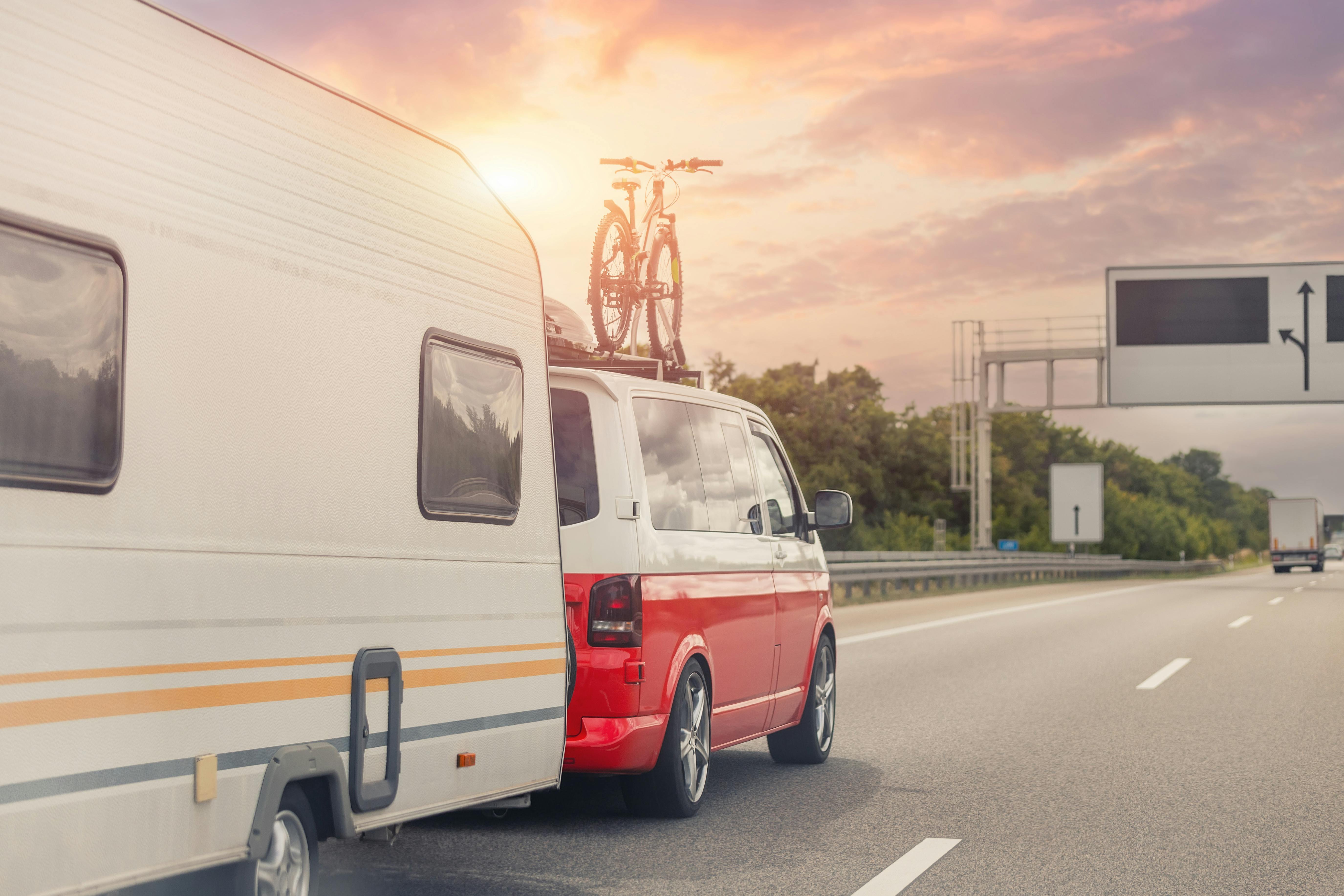 A picture of a van with a bicycle strapped to its roof hauling a caravan on a dual carriageway