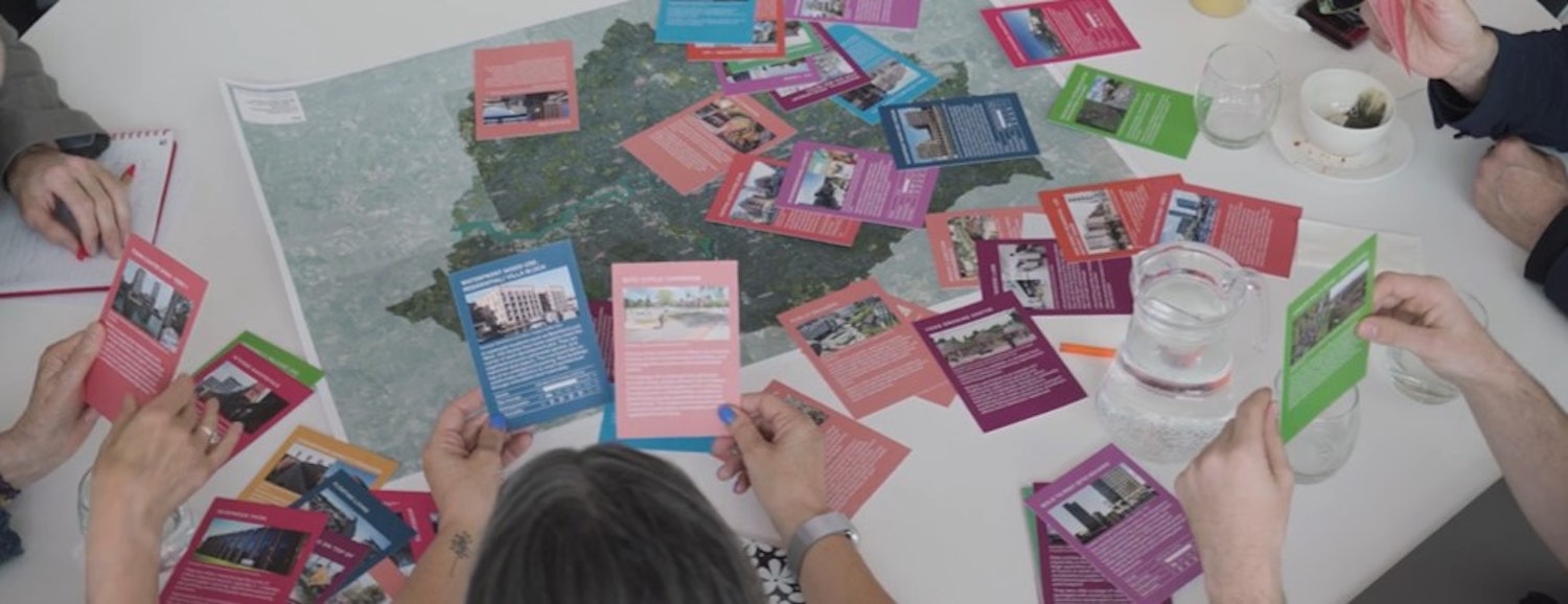 People around the table with cards working with cards showing different types of development and a map of London