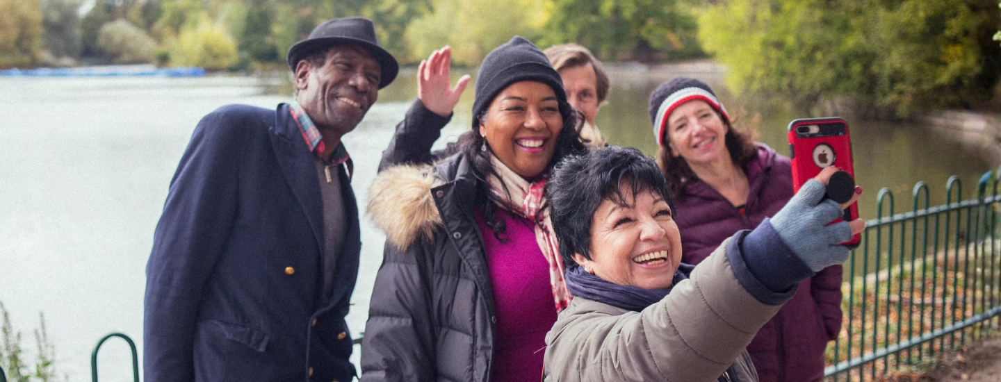 5 people are smiling and taking a selfie together by a lake