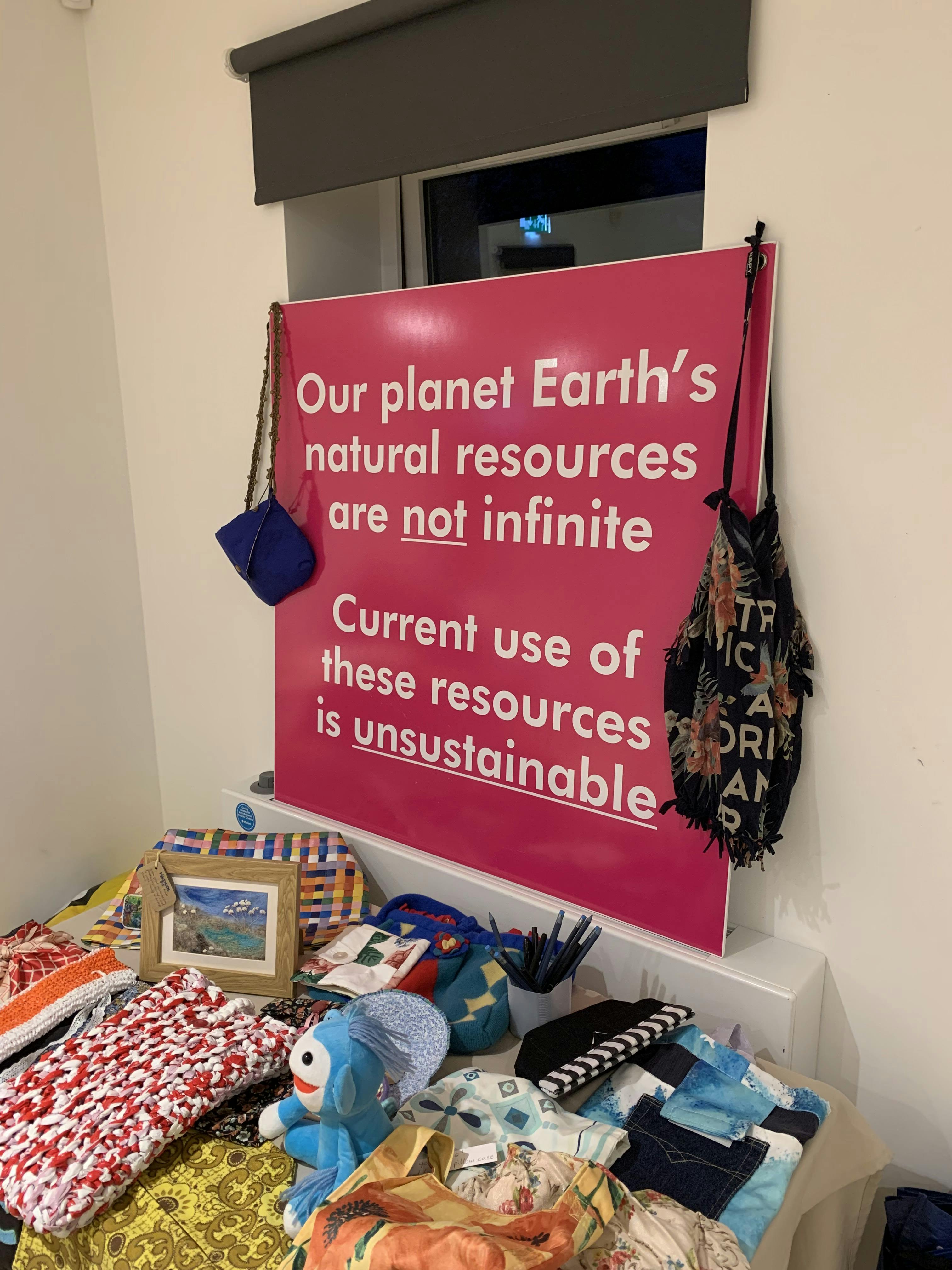 A pink Waste Prevention sign with the wording "Our planet Earth's natural resources are not infinite. Current use of these resources is unsustainable"