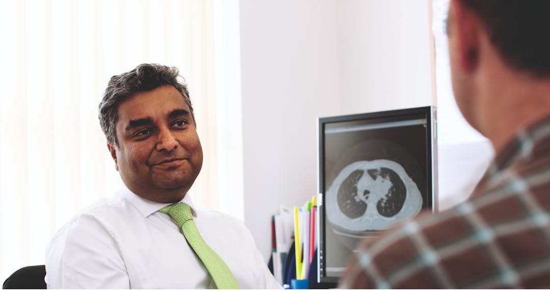 Consultant speaking to patient in front of computer screen with results of an imaging scan