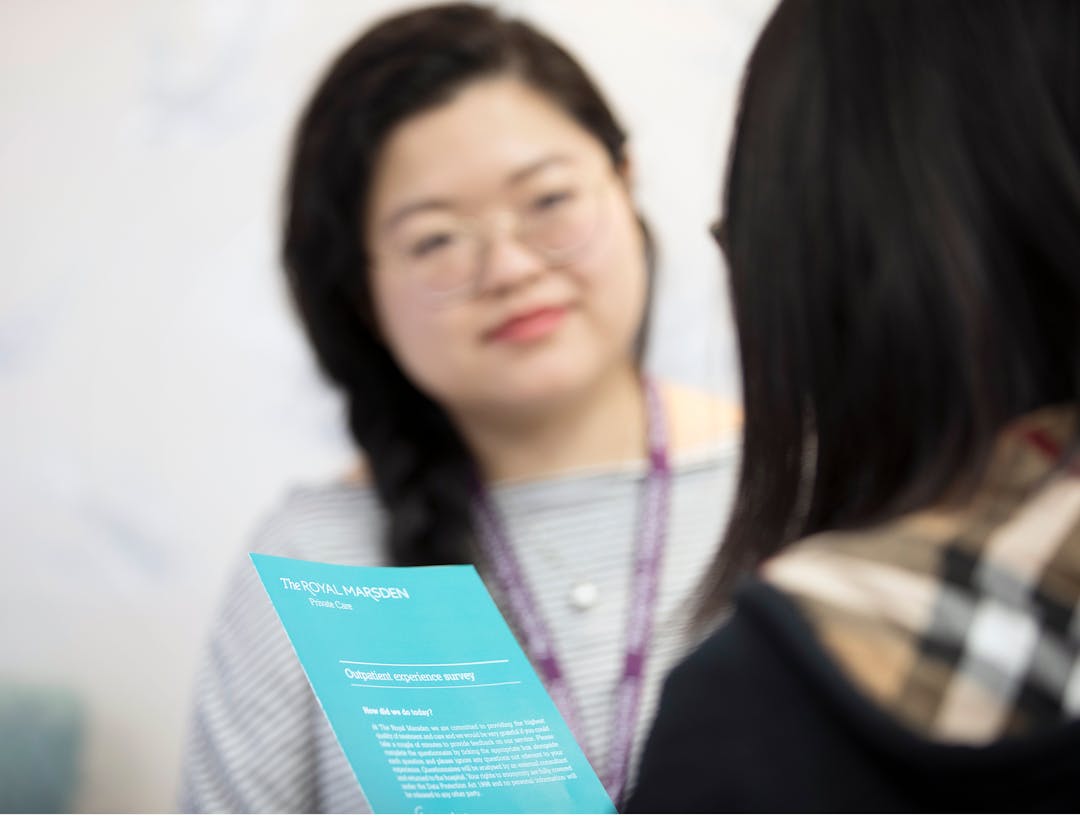 Patient holding paper questionnaire sitting with NHS staff member