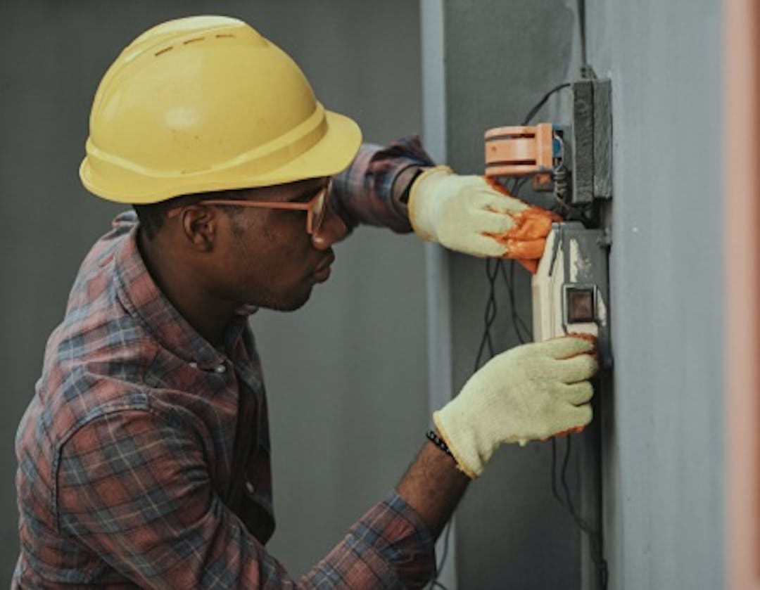 A repairs operative wearing a hard hat and protective eyewear carrying out an electrical repair