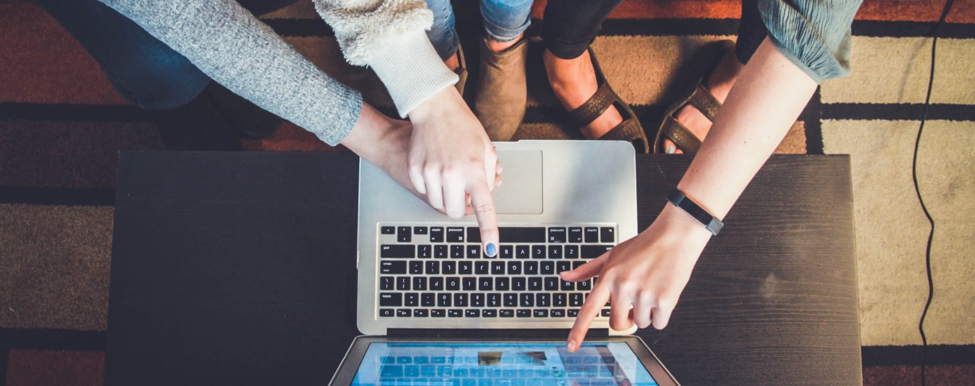 Aerial view of three women pointing at a laptop screen