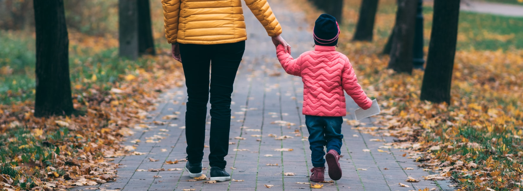 Woman and child walking along a leafy path