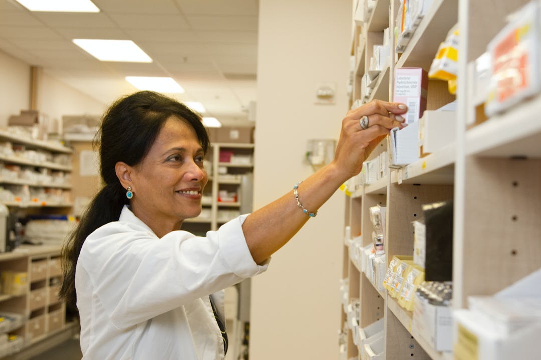 Lady pharmacist looking at boxes of medicine