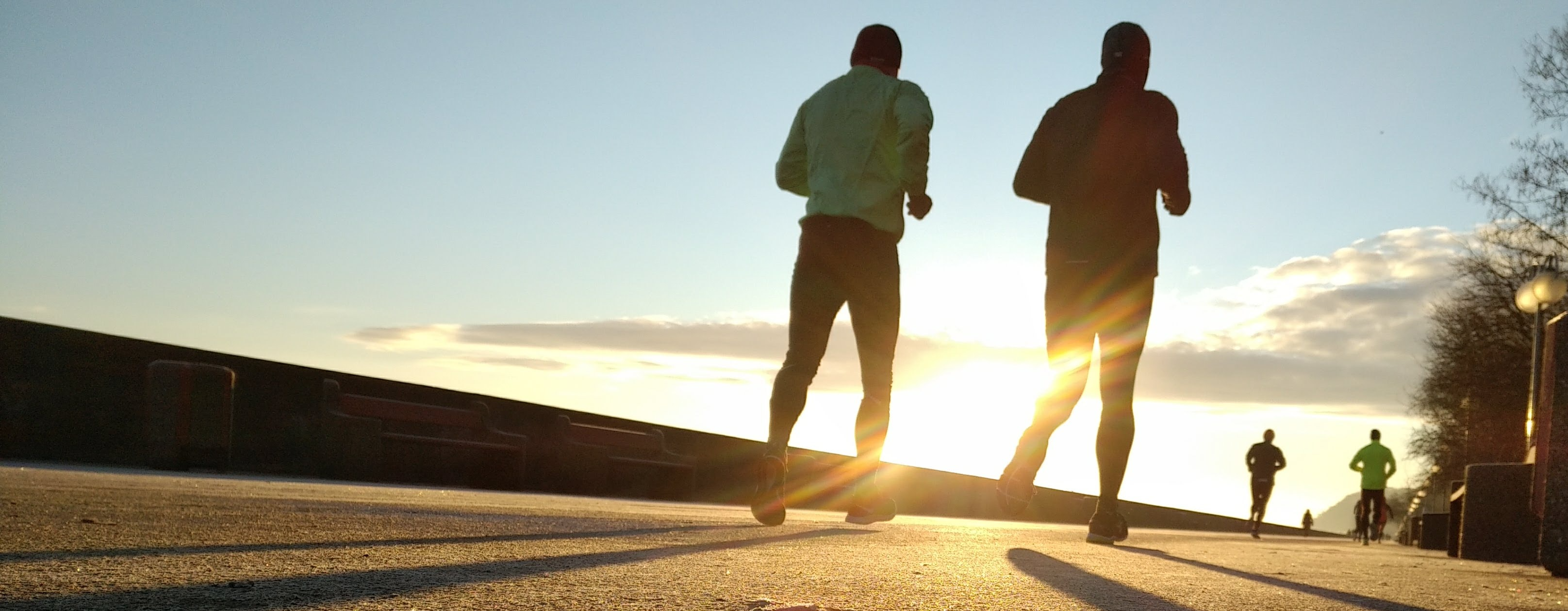 Four runners silhouetted against the sunset.
