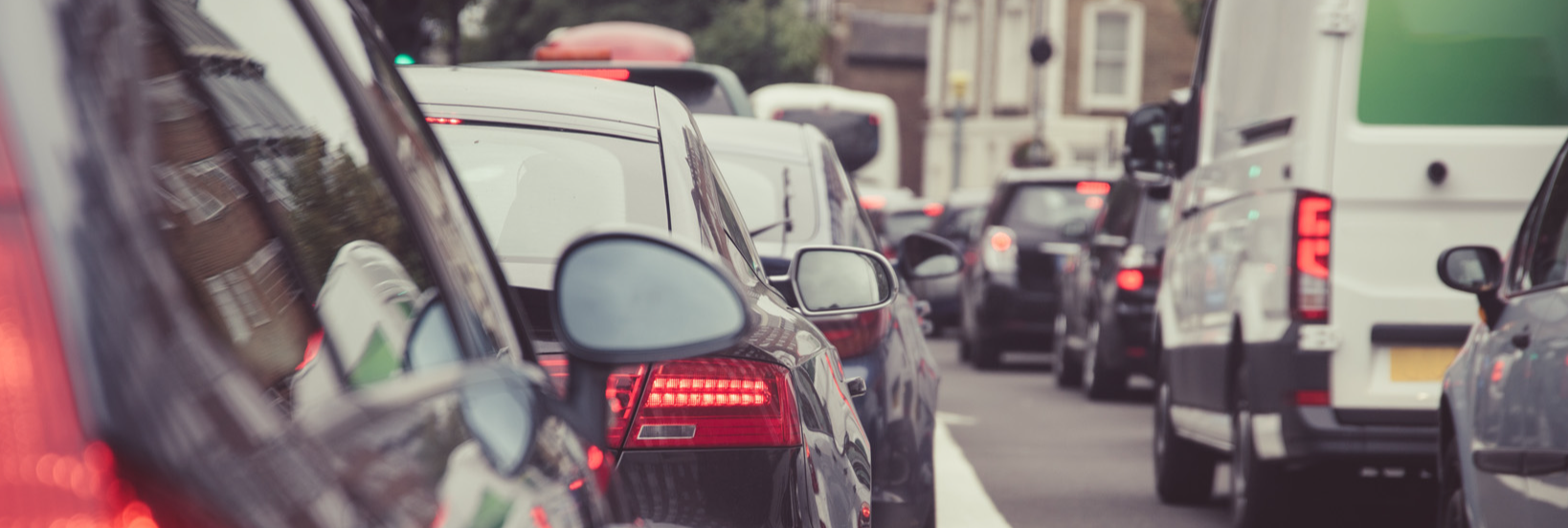 An image of  a row of cars and vans in a traffic jam on a road