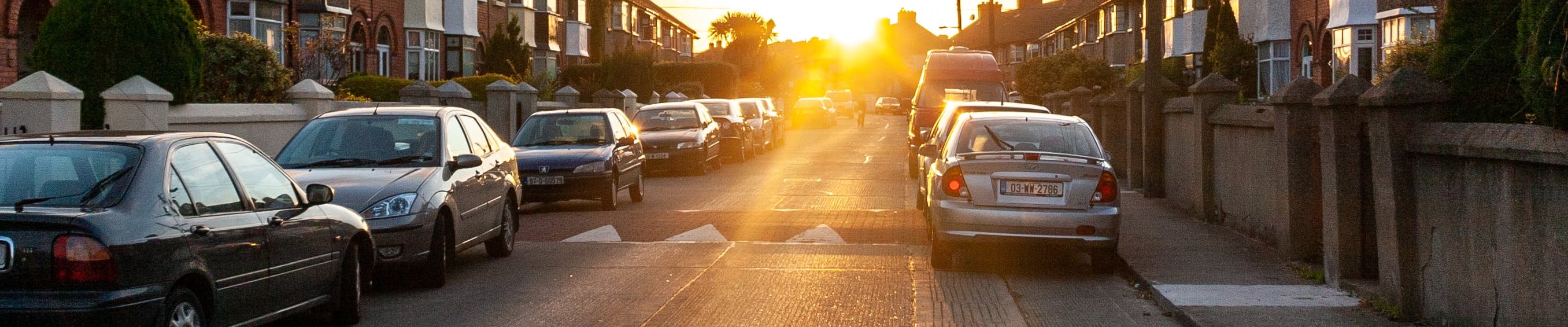 Residential street with parked cars on either side of the road