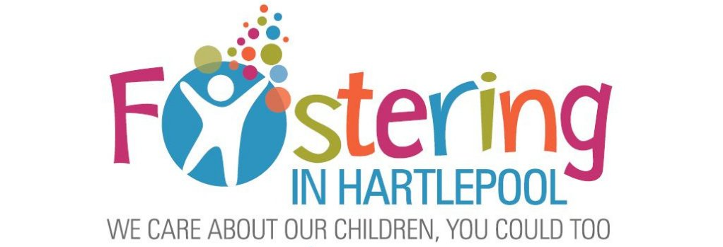 A woman with long blond hair and glasses helps a teen in a pink jumper with their school work