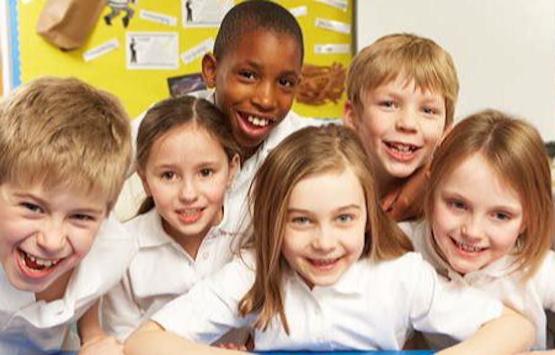 A group of young school children together in a classroom.