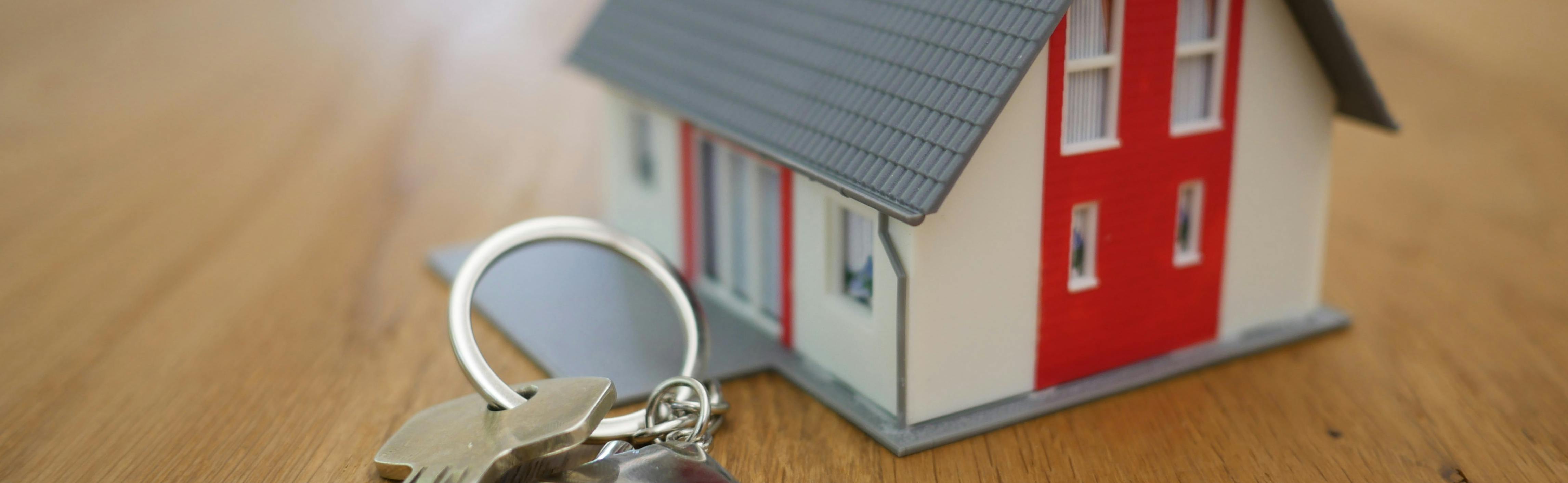 Picture showing a model of a house, next to a padlock and keys