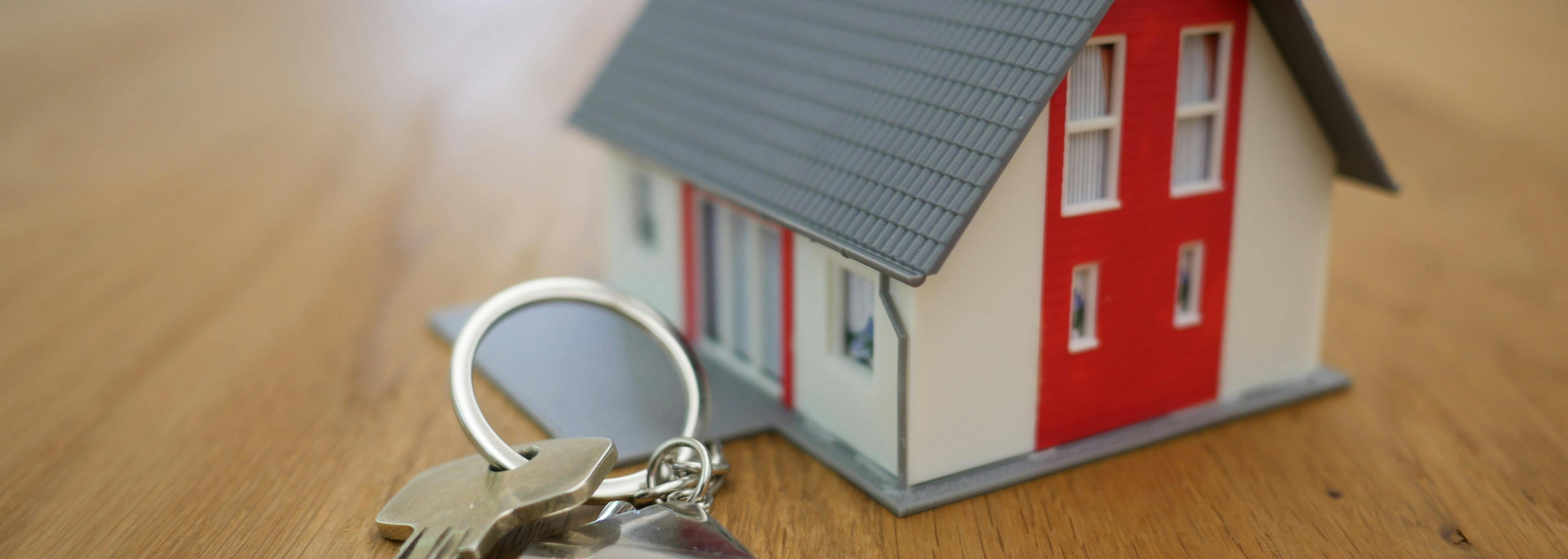 Picture showing a model of a house, next to a padlock and keys