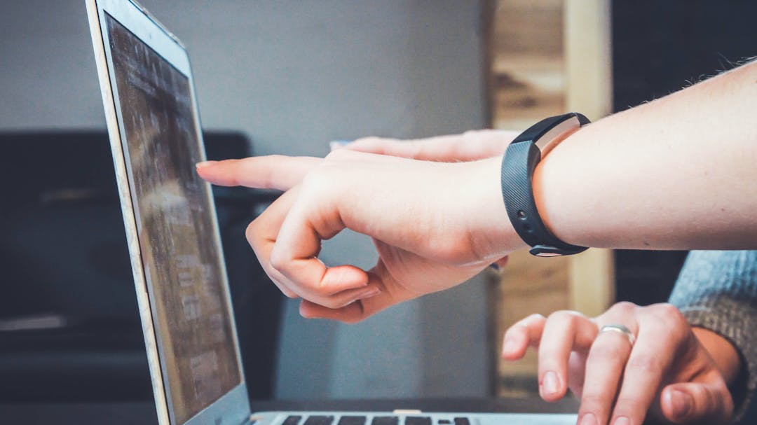 Laptop with two hands pointing at the screen