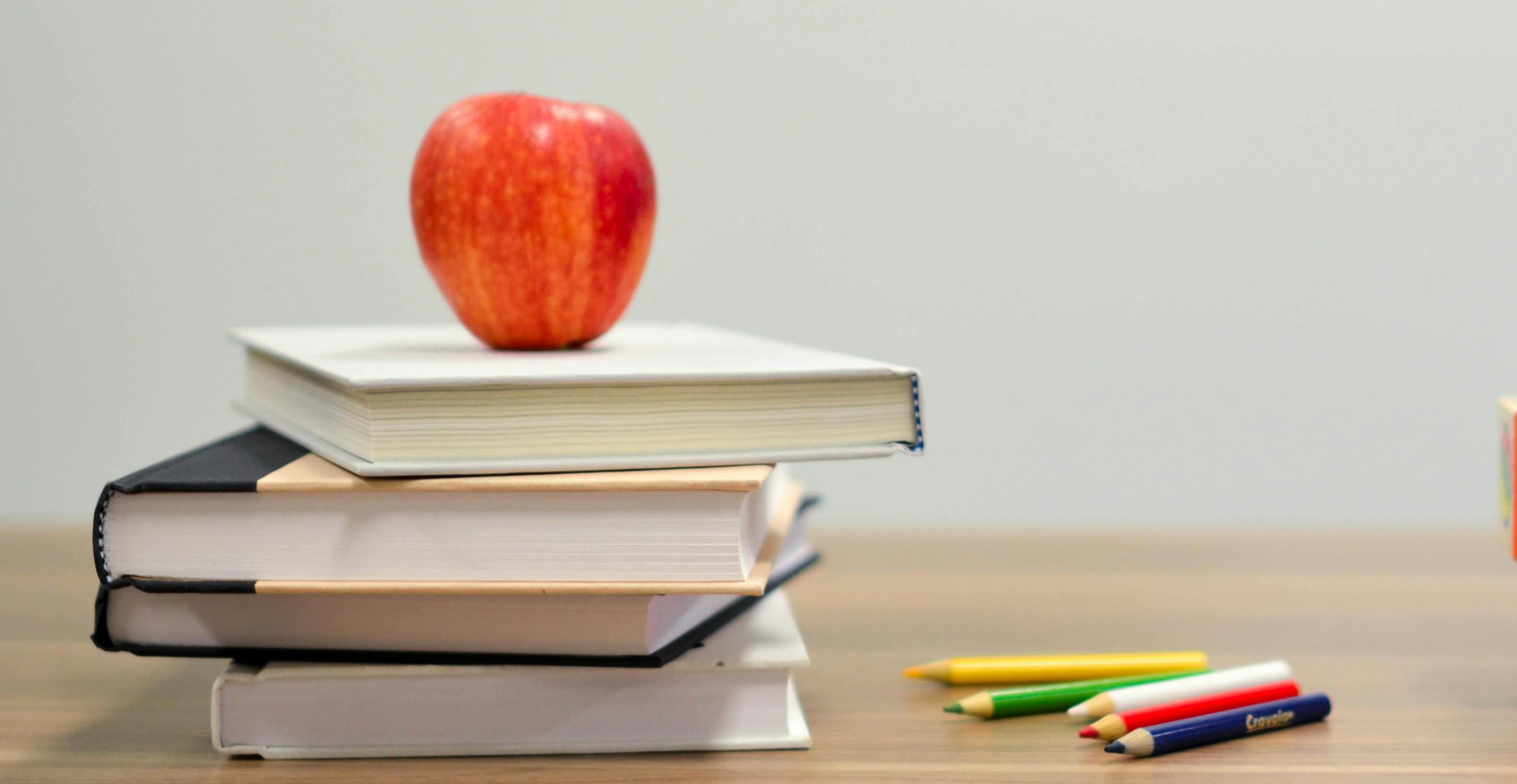 Apple and books on a desk.