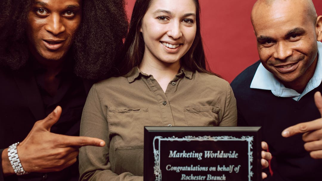 Person holding certificate with two people pointing at the certificate