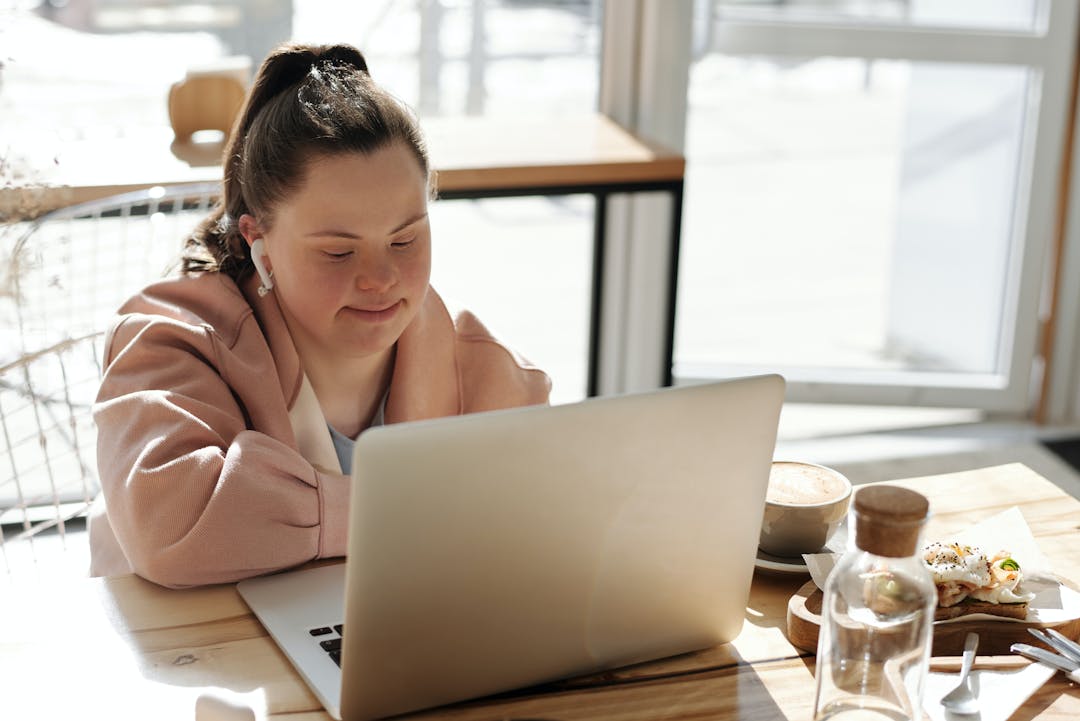 Woman sitting at a table using a laptop.